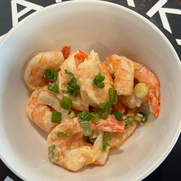 Kanaka's creamy shrimp poke with green onions in a white bowl.