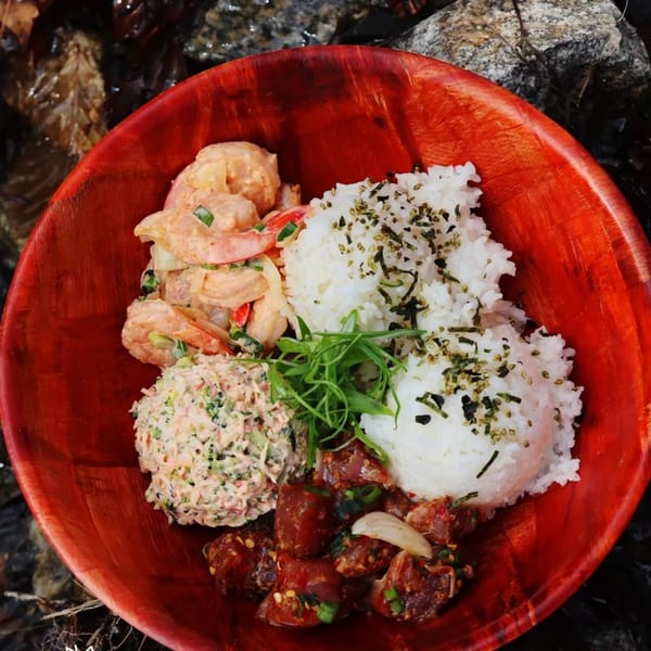 Kanaka poke bowl with shrimp, tuna, crab salad, and rice in a red bowl.