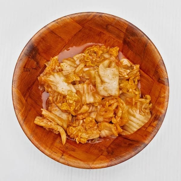 Kimchi, a traditional Korean side dish, served in a wooden bowl at Kanaka.