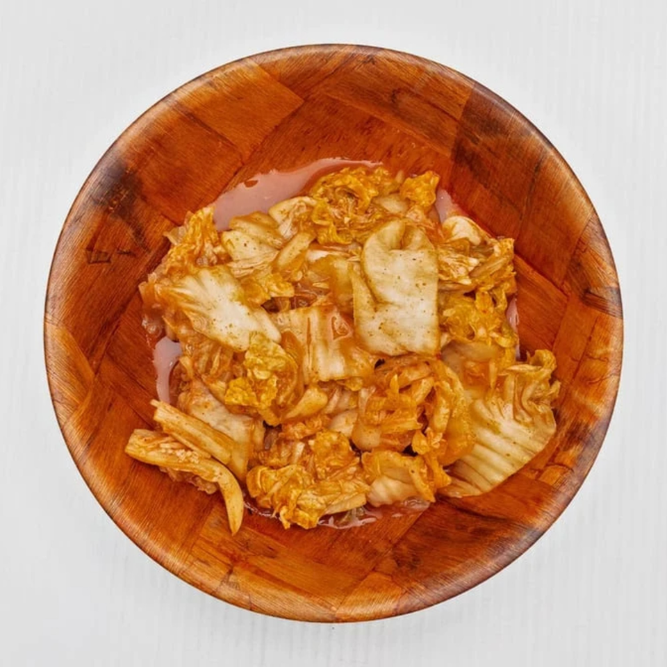 Kimchi, a traditional Korean side dish, served in a wooden bowl at Kanaka.
