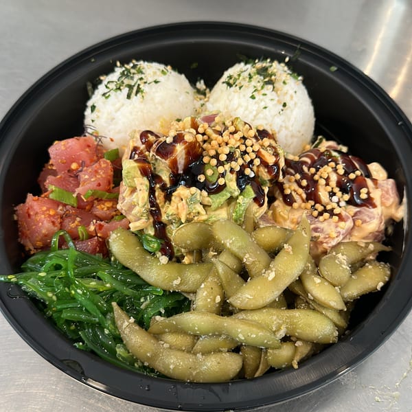 A Kanaka poke bowl with tuna, rice, edamame, seaweed salad, and various sauces and toppings.