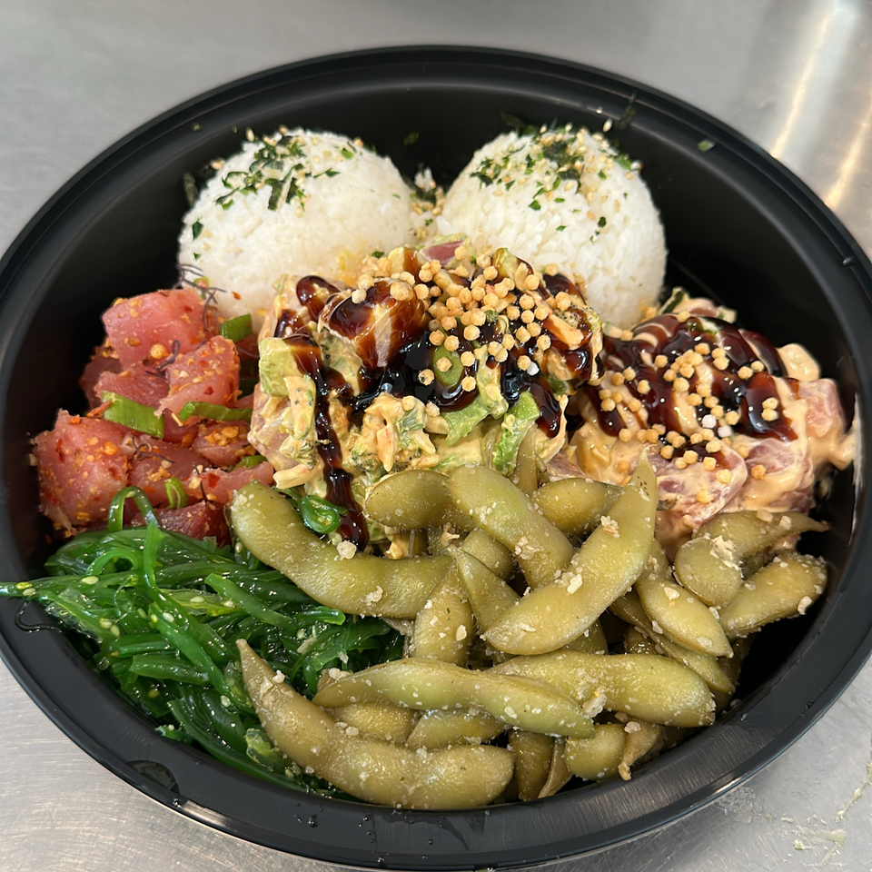 A Kanaka poke bowl with tuna, rice, edamame, seaweed salad, and various sauces and toppings.